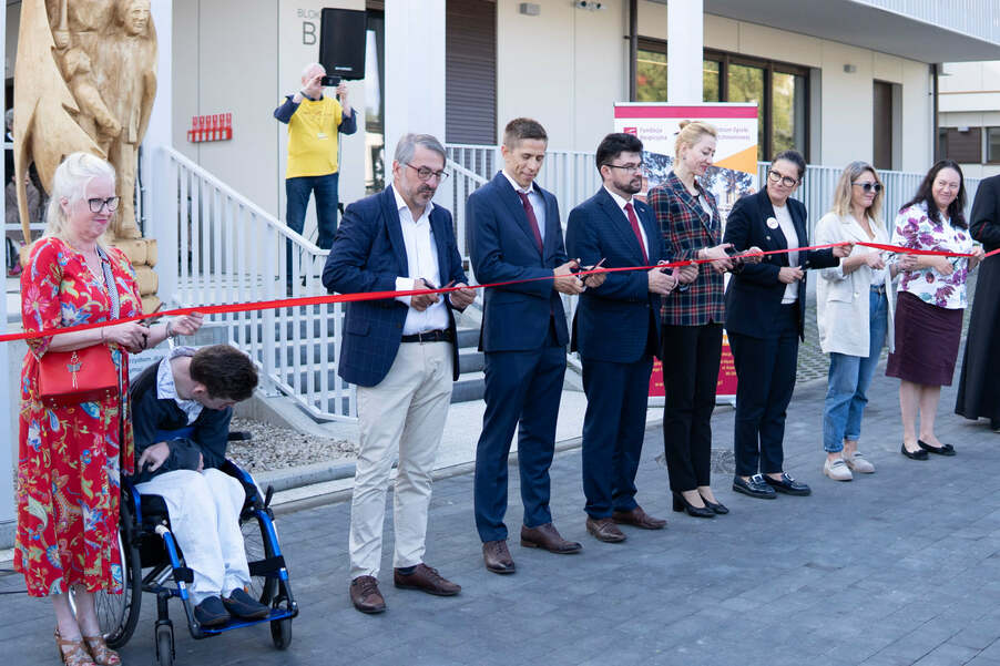 cutting the ribbon under the Respite Care Center building